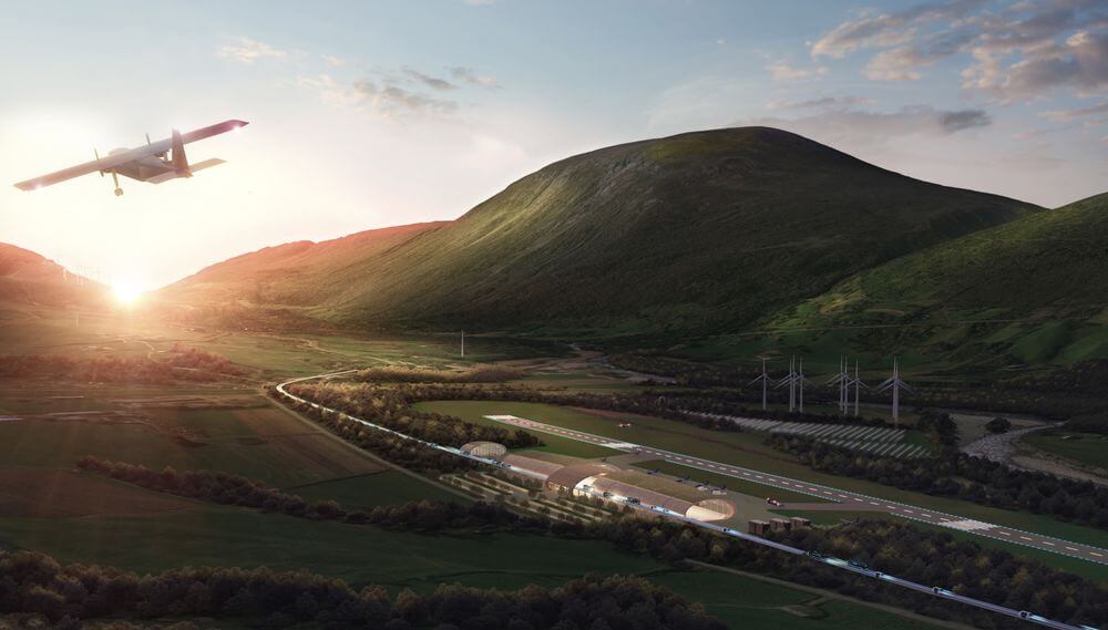 Aircraft flying over green hydrogen infrastructure facility with wind turbines and storage tanks in valley landscape at su...