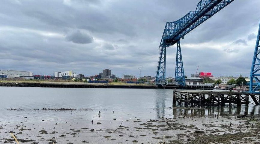 Tees Valley industrial waterfront with iconic transporter bridge, riverside facilities, and cloudy sky, representing Proti...