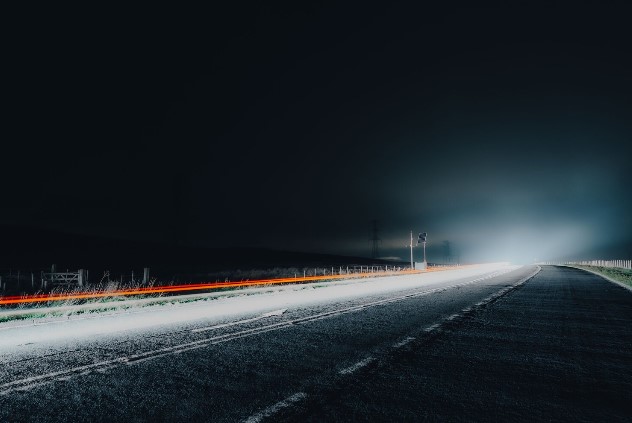 Modern highway at dusk with illuminated barriers and suspension bridge in distance, representing Kier's net zero highways ...