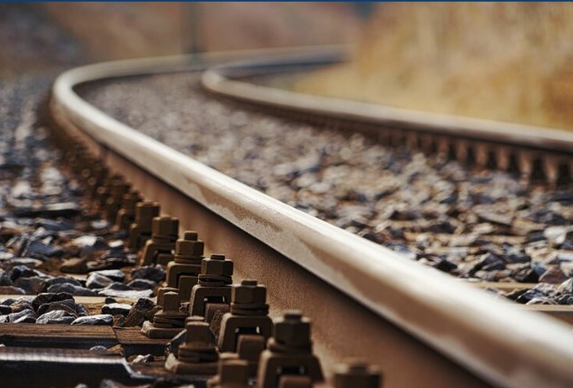 Close-up of railroad tracks and metal rails with ballast stones, illustrating rail infrastructure for decarbonization disc...