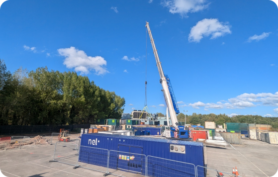 Hydrogen South Wales industrial facility with blue equipment and crane against clear sky and tree-lined horizon.