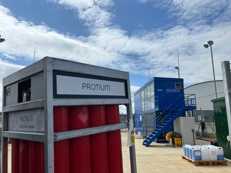 Protium hydrogen fueling station and OXCCU blue facility with equipment on outdoor industrial site under blue sky.